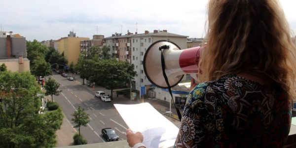 Sängerin mit Megaphon singt vom Kirchturm herunter